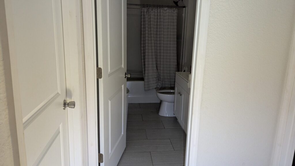 View into a modern bathroom with a tub, shower curtain, and toilet.