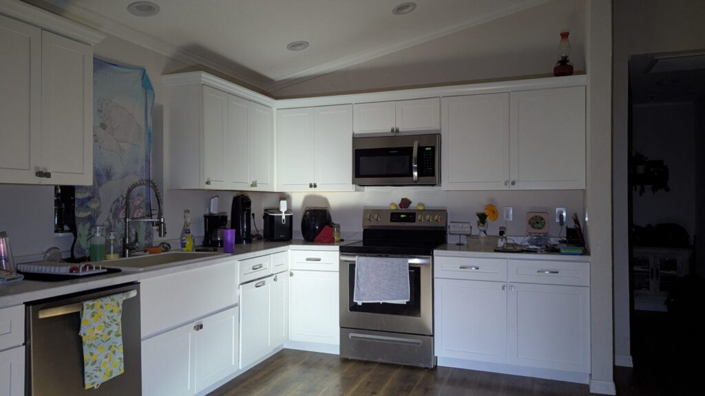 Well-lit photo of a modern kitchen with white cabinets and stainless steel appliances.