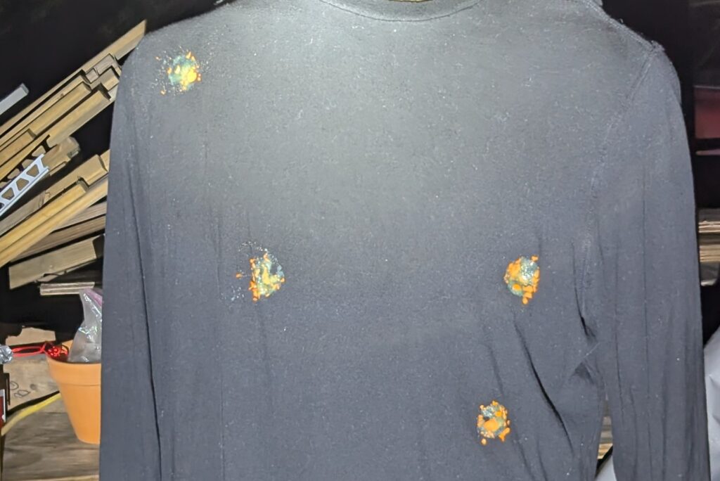 Black long-sleeve shirt with four brightly colored impact marks.