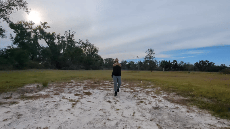 Man drawing and aiming handgun while walking forward outdoors