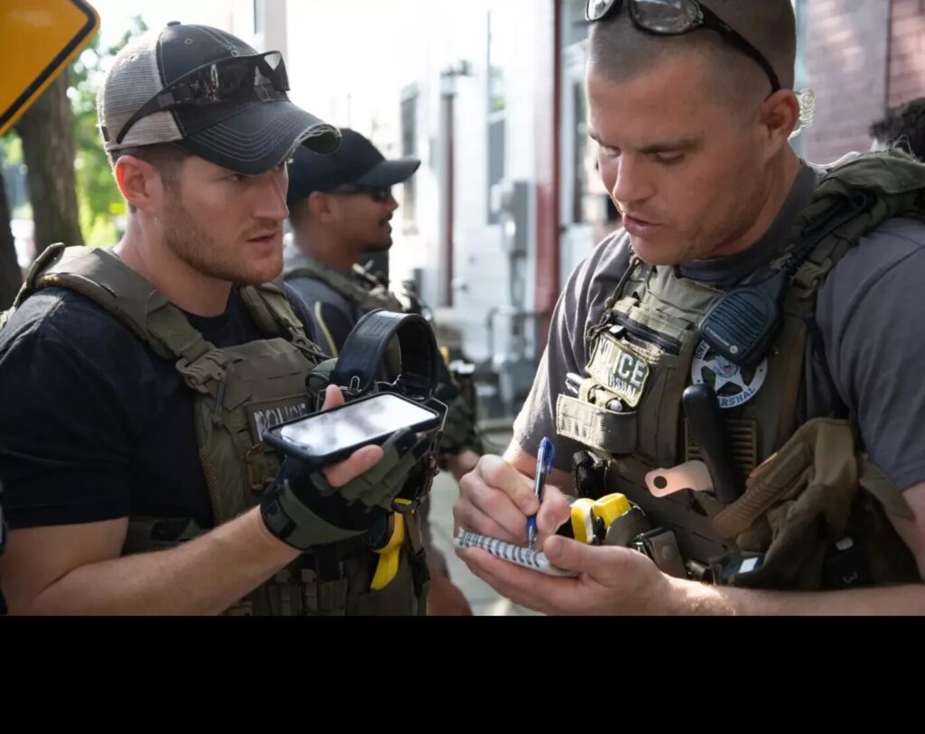 Deputy U.S. Marshals talking and taking notes during Operation North Star, a high-impact fugitive apprehension initiative aimed at combating violent crime in 10 cities with a significant number of homicides and shootings.