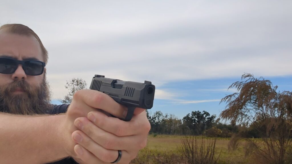 Hand holding and aiming the compact black SIG P365 BB pistol