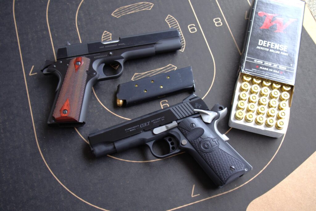 colt night commander pistol with a colt government model 45 pistol and a box of ammunition