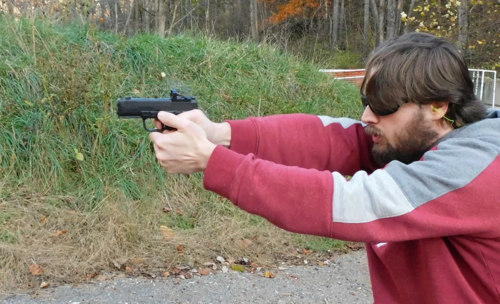 Man firing a pistol on a range