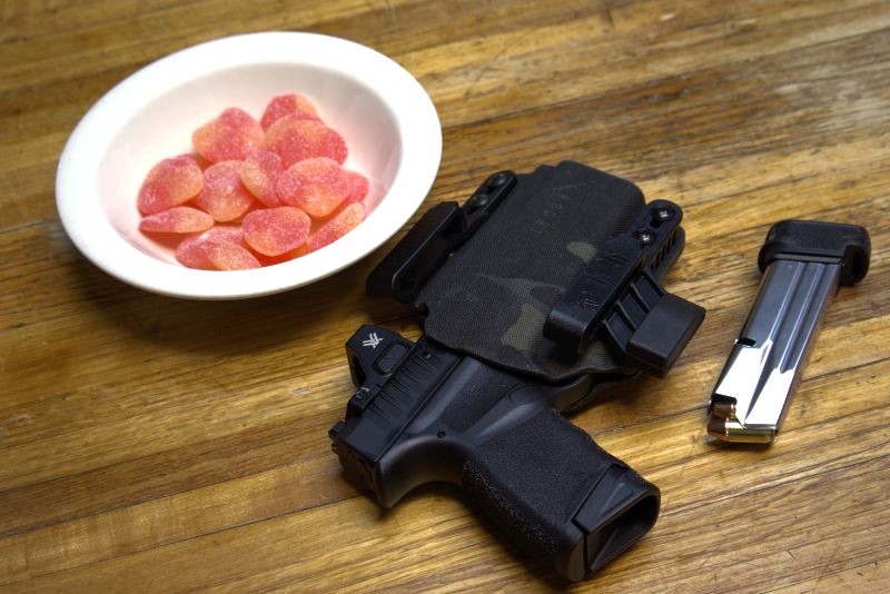 springfield hellcat in a safariland incogx holster on a table next to a bowl of candy and a magazine