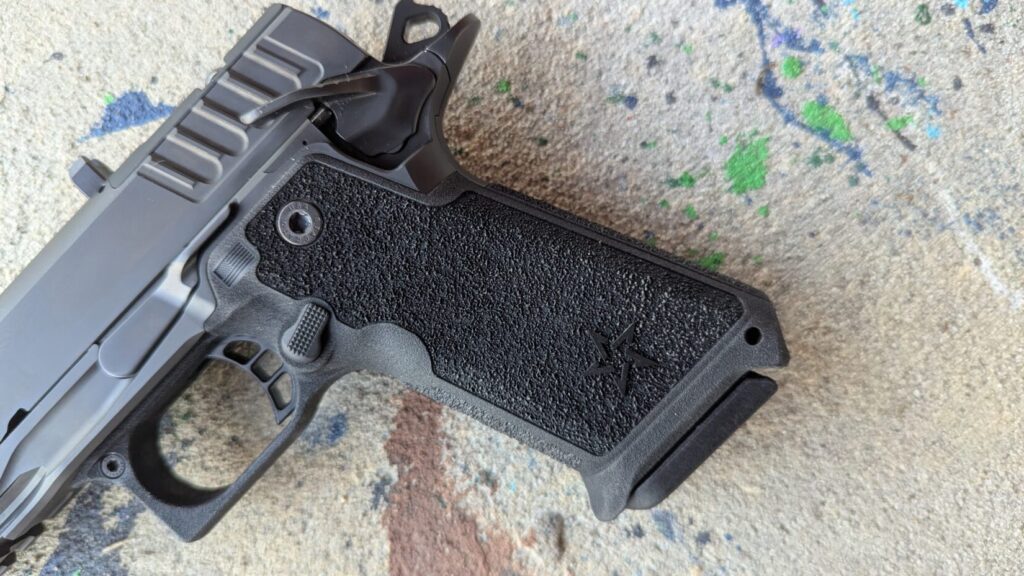 Close-up view of the textured polymer grip module and frame of a Staccato HD pistol resting on a concrete surface