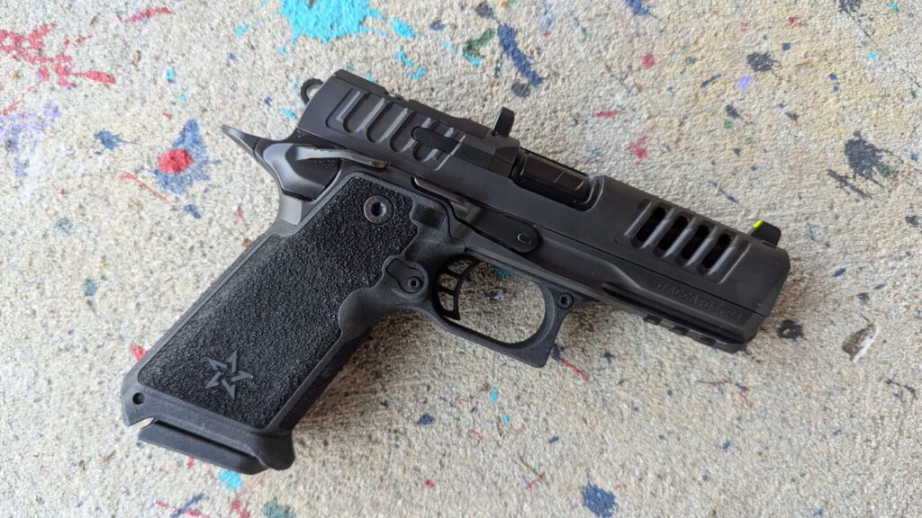 Top-down view of the black Staccato HD P4 pistol, showing the full slide and grip, resting on concrete with paint splatters.