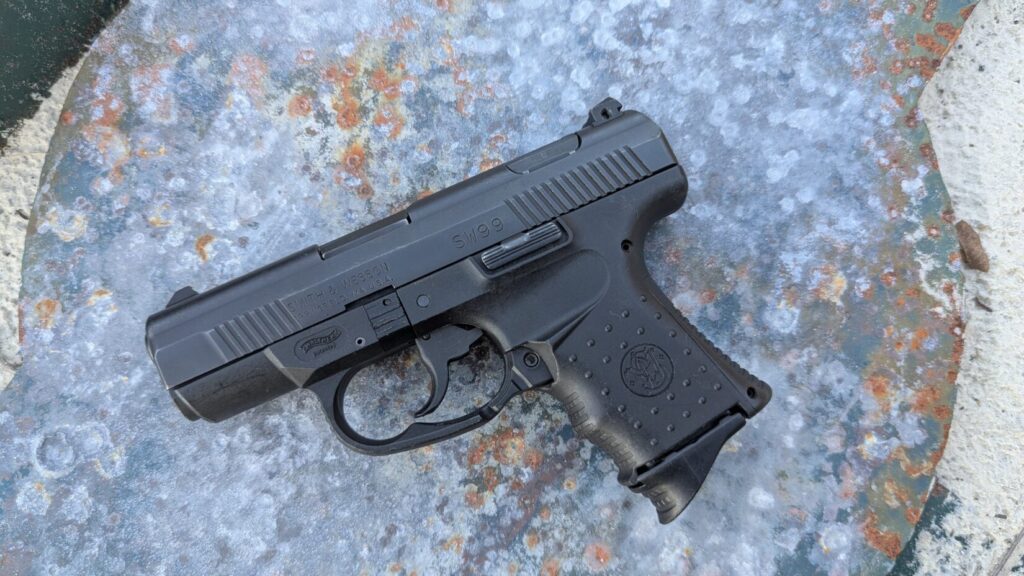  Black compact pistol (SW99) lying on a blue concrete surface
