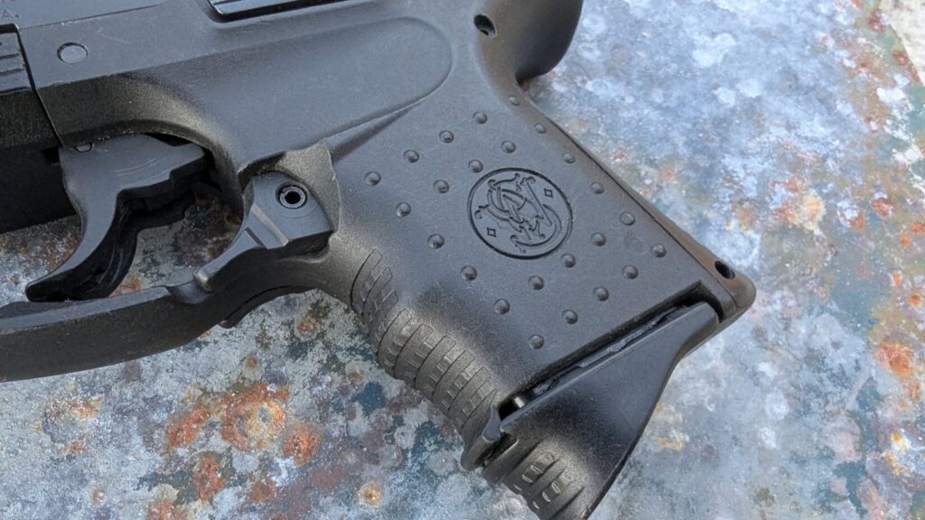 Black compact pistol (SW99) lying on a blue concrete surface.