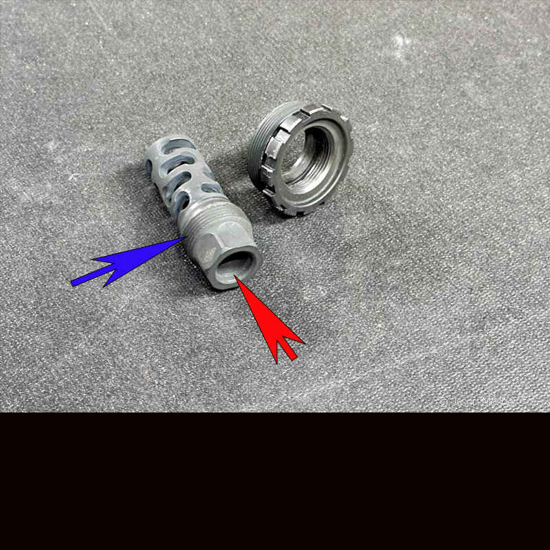A muzzle device next to a silencer mount on a grey table. 