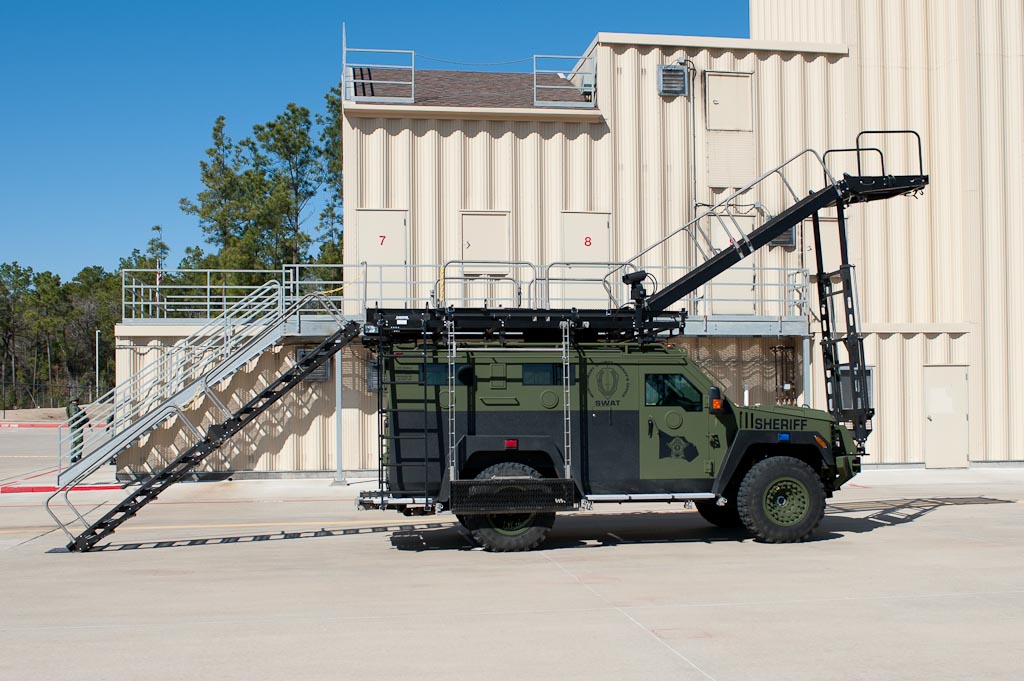 Green and black Lenco BearCat SWAT vehicle with a retractable platform/ramp deployed.