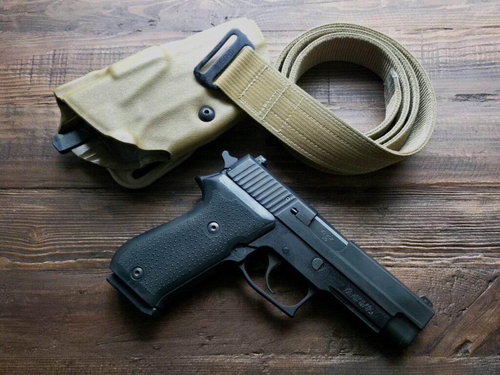 A pistol, holster, and belt on a wooden table