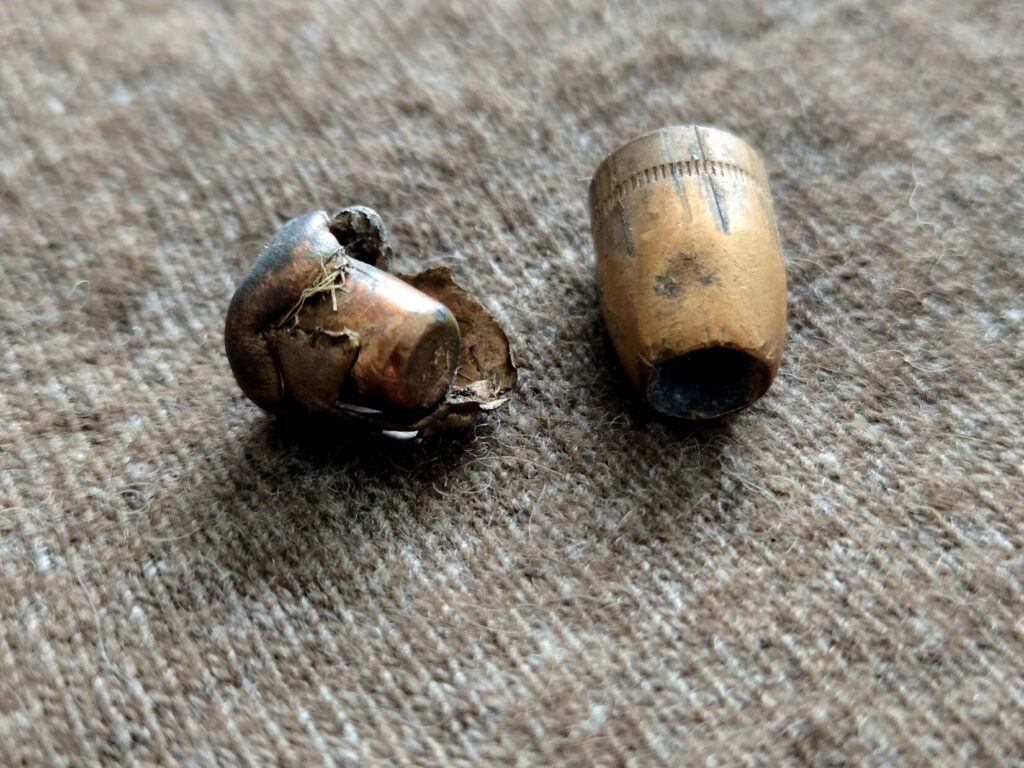 A rifle bullet and a pistol bullet on top of wool back drop