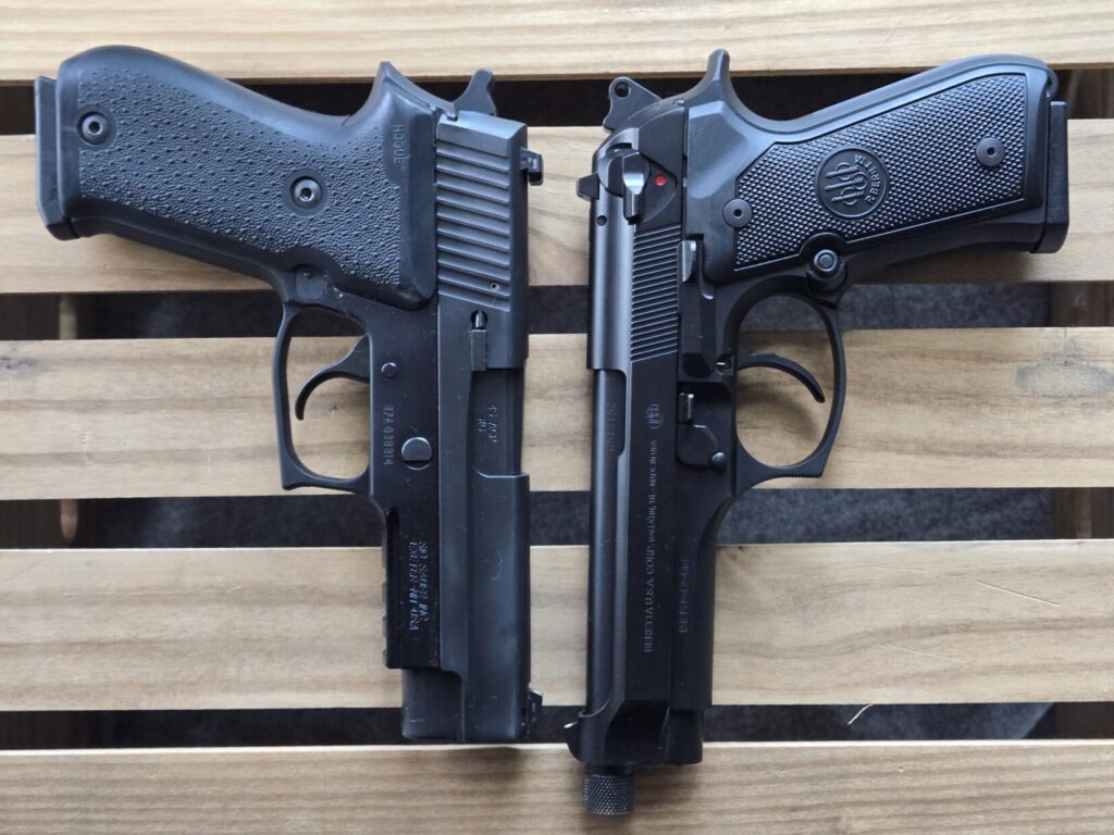 A SIG P220 and a Beretta 92FS on top of a wooden crate