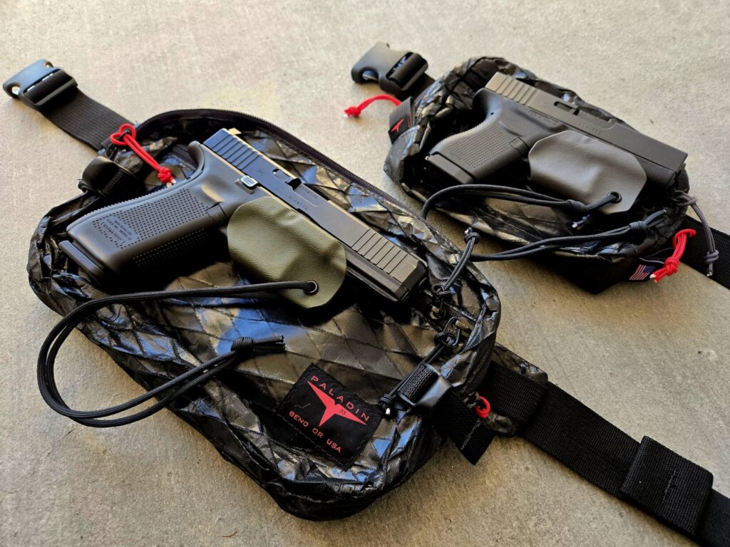 Two glock pistols on top of two different sized fanny packs