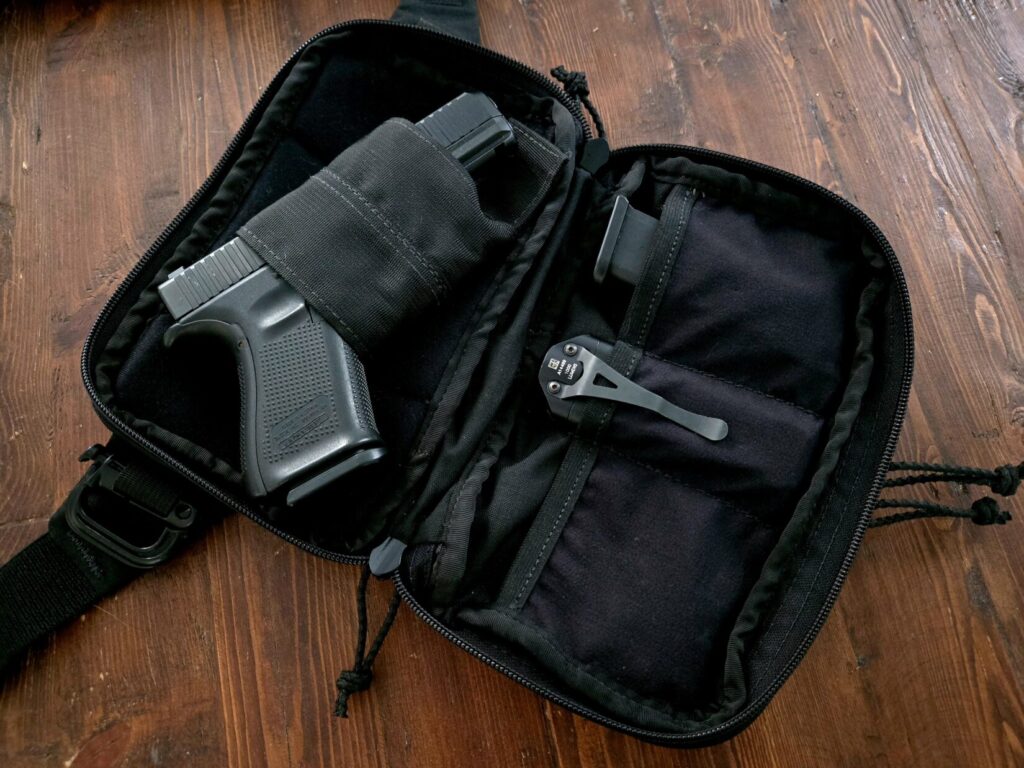 A Glock pistol inside of a fanny pack with a Surefire light and spare magazine.