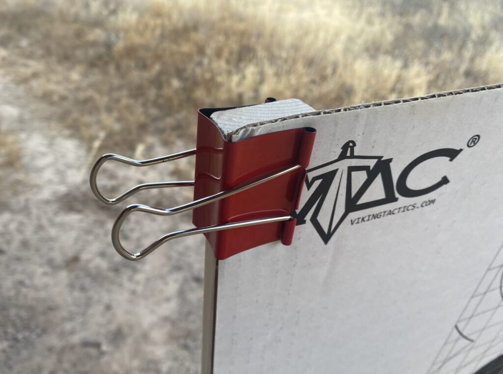 Standard large binder clips, available at any office supply store, are a great way to attach a backer or cardboard target to the uprights.