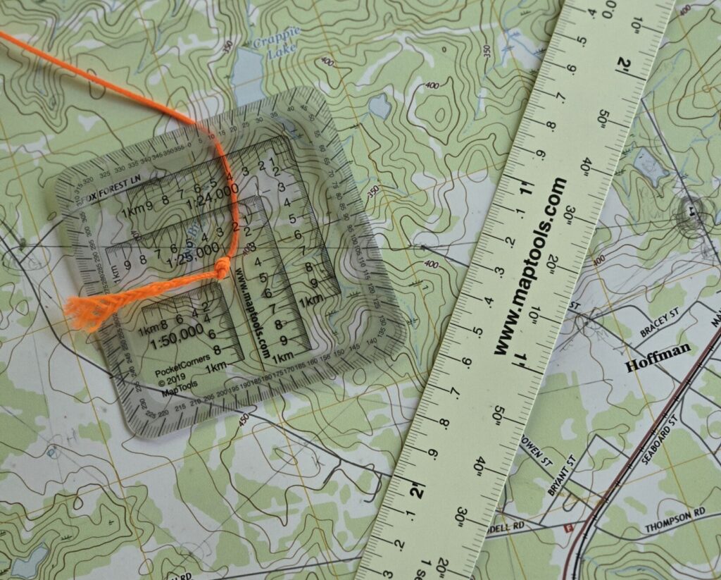 A map protractor along with a map ruler on top of a topographic map.