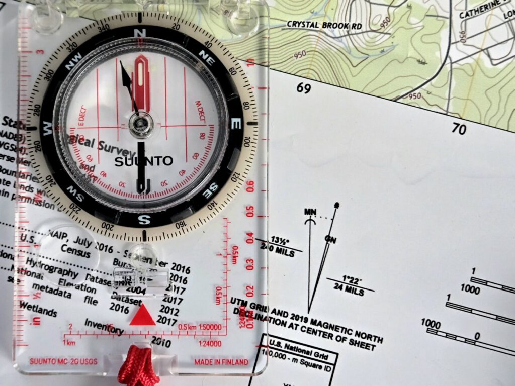 A baseplate compass on top of a map next to the North arrows.