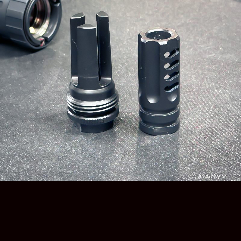 A muzzle device with threads on the outside and one without threads on the outside, set next to each other on a grey table. 