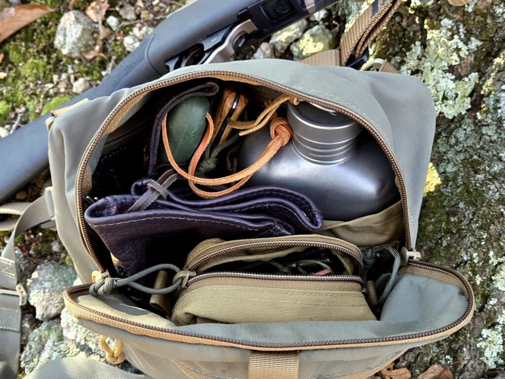 The contents of a shoulder bag with a rimfire rifle in the background