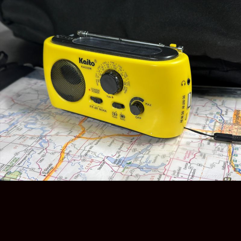 A yellow radio sitting on a map. 