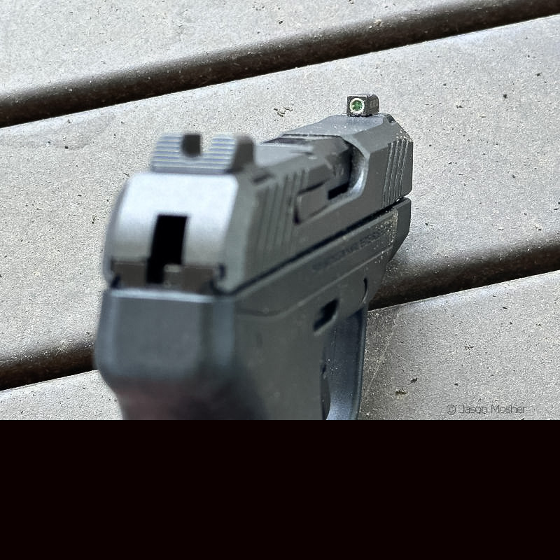 Close-up of a handgun's fixed iron sights, showing the notched rear sight and front sight post