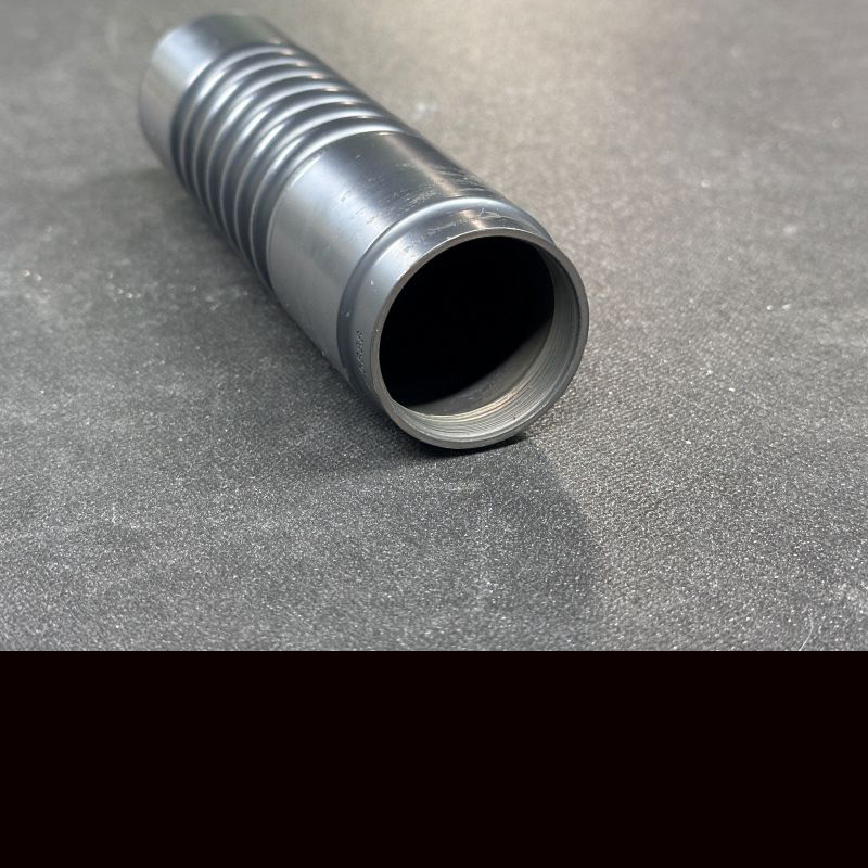 A silencer on a grey table with no back on the silencer, showing the open tube. 