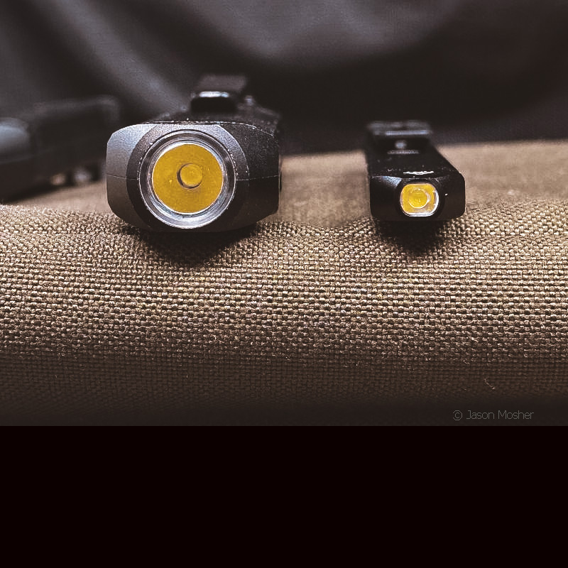 Two small flashlights on a green surface, showing how they compare in size to one another. 