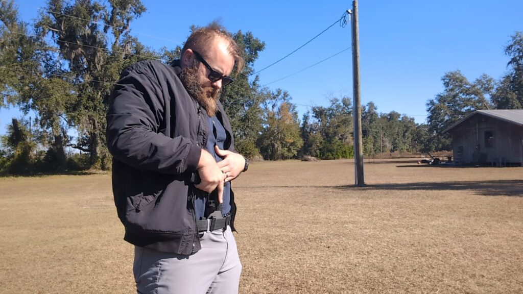 Man looking down while placing or adjusting pistol in appendix carry holster.