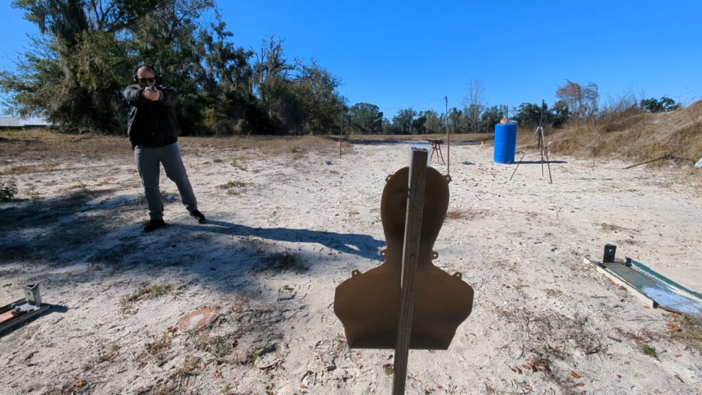 Shooter engaging steel target, seen from behind target.