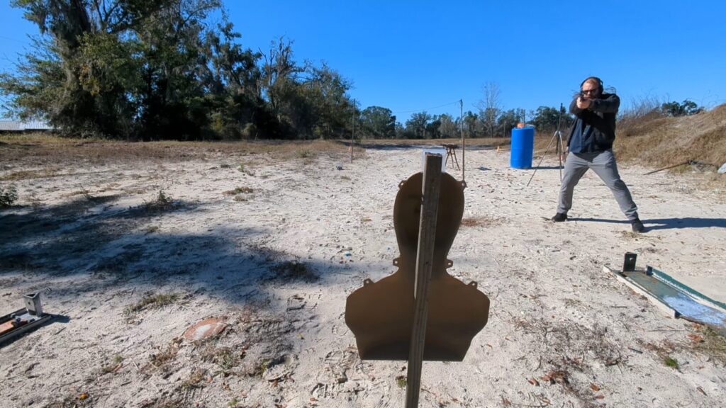 Shooter engaging distant target, view from behind steel target.