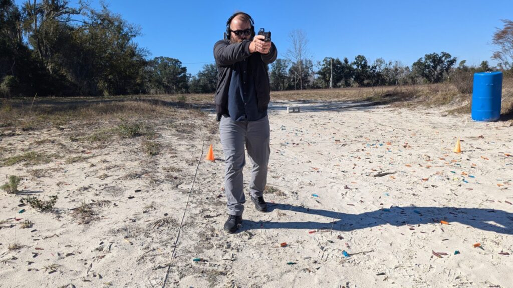 Shooter moving laterally, pistol aimed downrange.