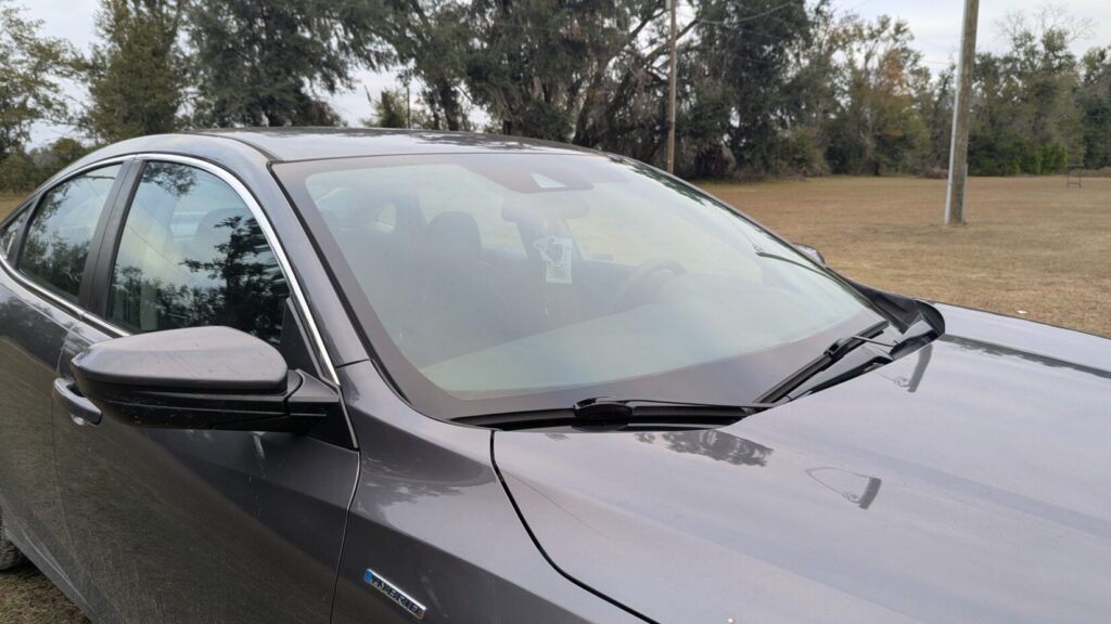 Close-up view of the windshield and hood of a dark gray sedan (Honda).
