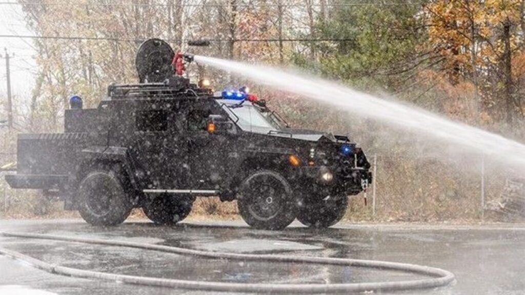 Black Lenco BearCat vehicle with a turret-mounted water cannon spraying a stream of water.