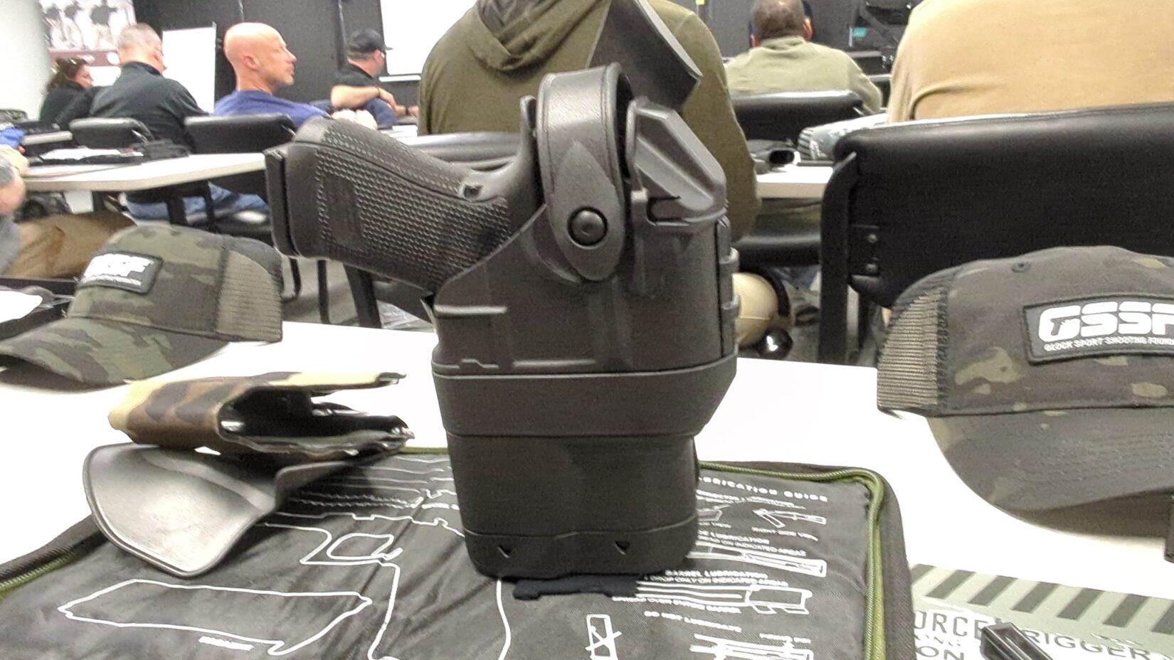 Black ballast holster containing a Glock pistol, resting on a gun cleaning mat.