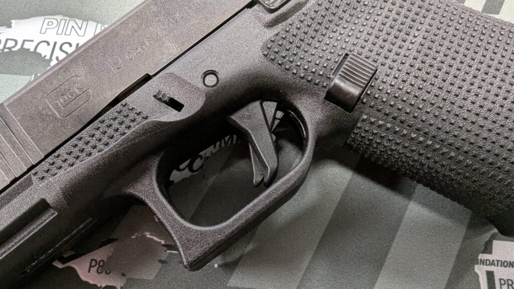 Extreme close-up of the textured grip and flat-faced trigger area of a Glock Gen 6 frame.