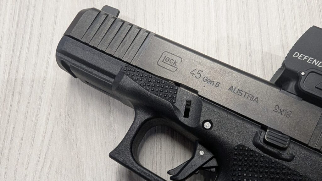 Close-up of the slide of a black Glock 45 Gen 6 pistol with an attached red dot optic.