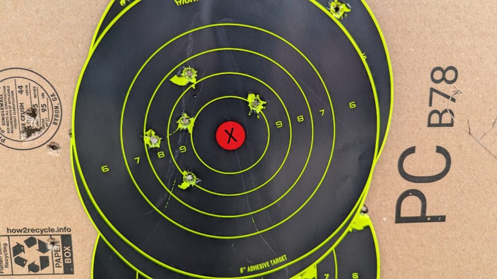 Close-up of a black and neon yellow target showing a tight grouping of bullet impacts in the center.