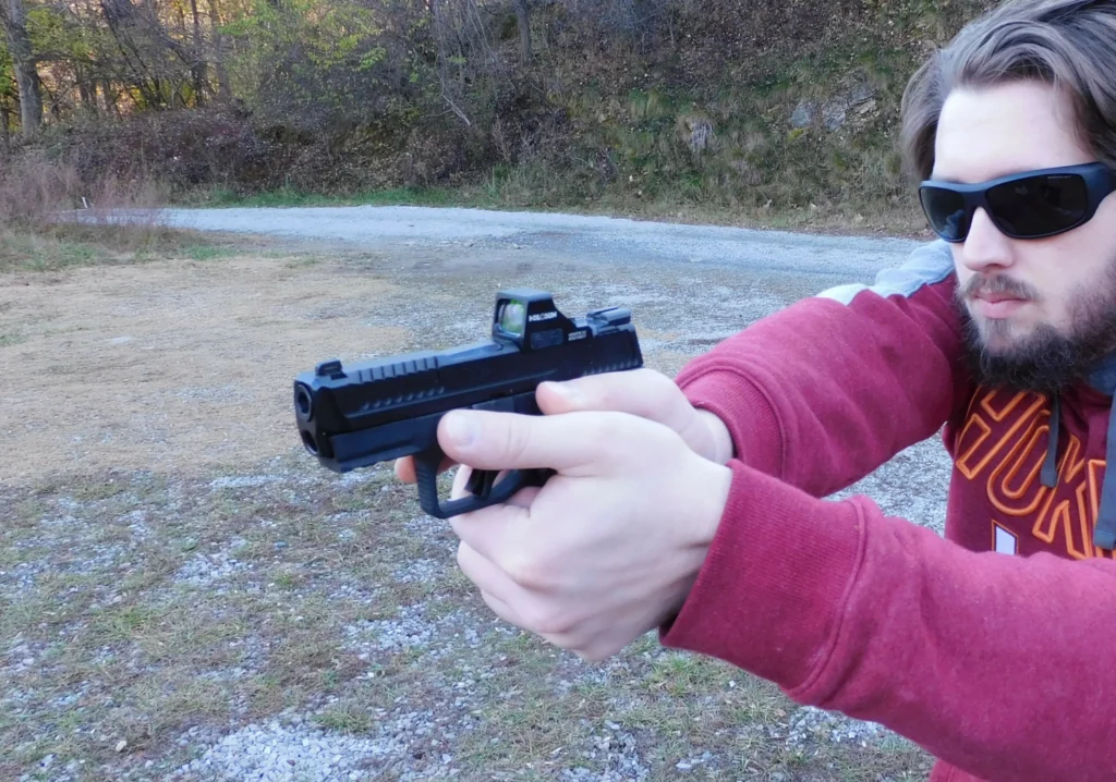 Man firing a semiautomatic pistol with a red dot optic