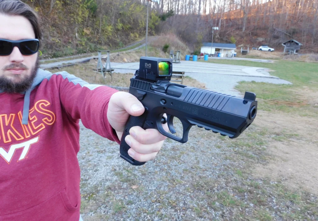Man firing an IWI Jericho 941 pistol with a red dot optic