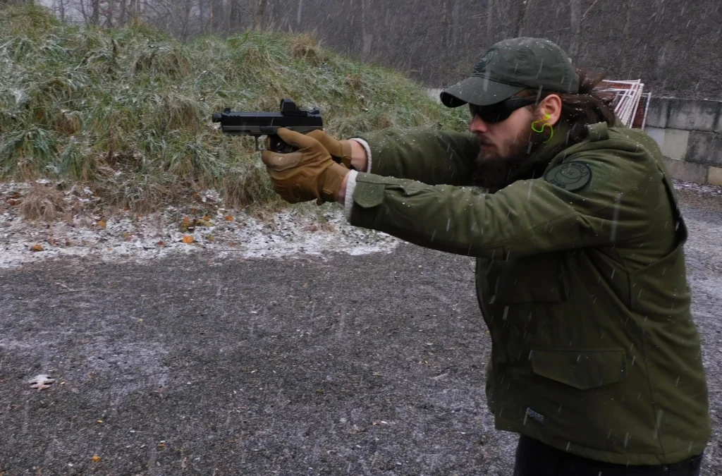 Man firing a semiautomatic pistol in the snow