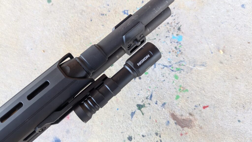 Close-up of the Modlite Havok mounted near the end of a shotgun barrel/forend.