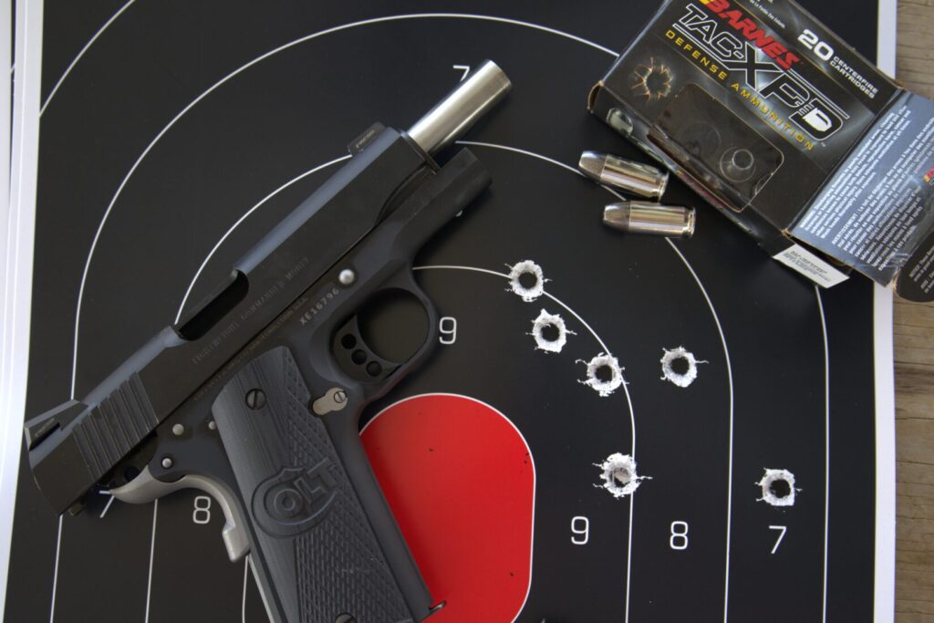 colt night commander with a paper target and a box of barnes ammunition