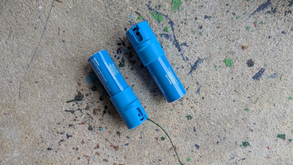 Two blue POM practice inert units lying on a concrete surface.
