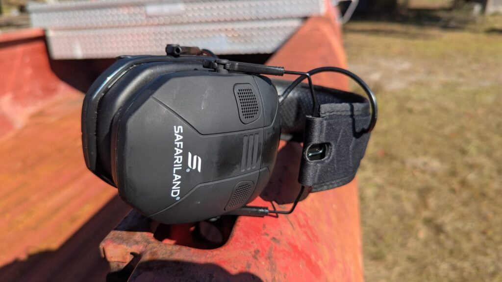 Close-up of Safariland electronic ear protection cup showing controls and microphone on a metal surface.