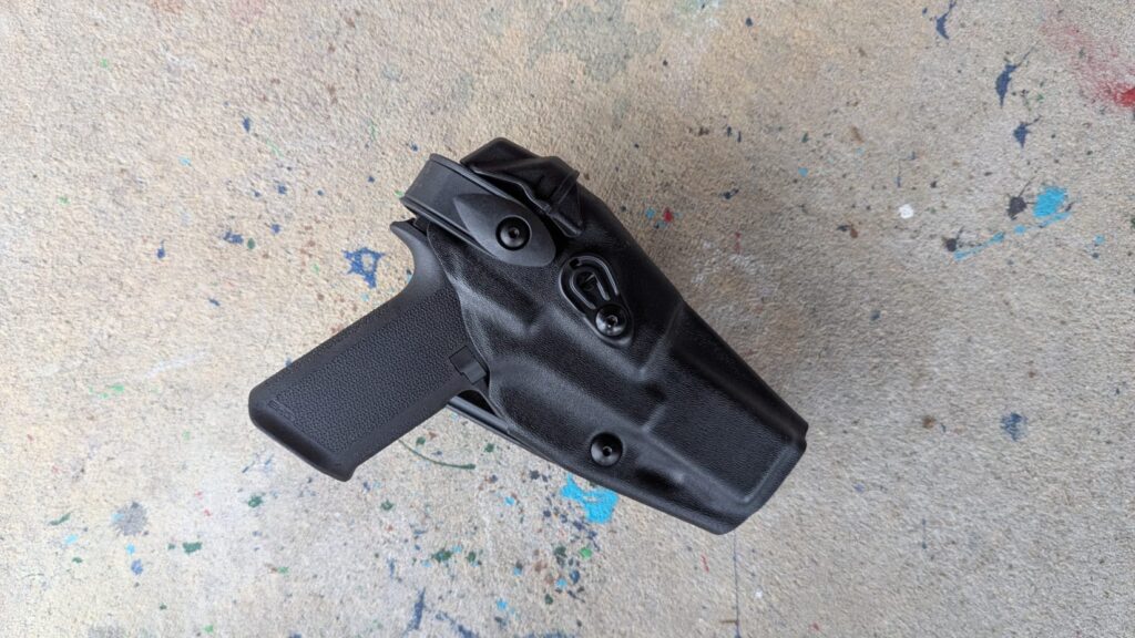 Black pistol holstered in a black OWB (Outside the Waistband) holster