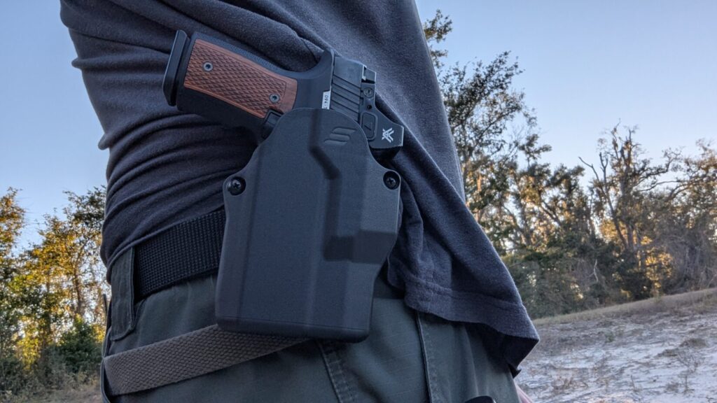 Sharps Bros pistol in a belt holster worn outdoors.