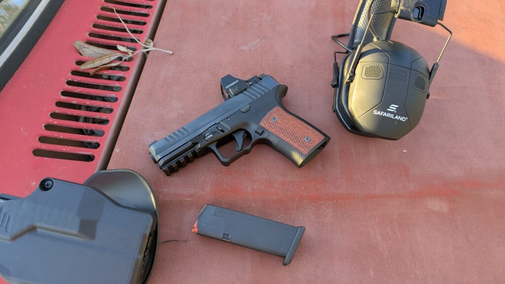 Sharps Bros pistol with ear protection and holster on a rusty surface