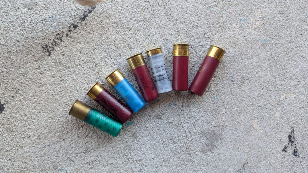 A variety of colorful shotgun shells lined up diagonally on a concrete surface.